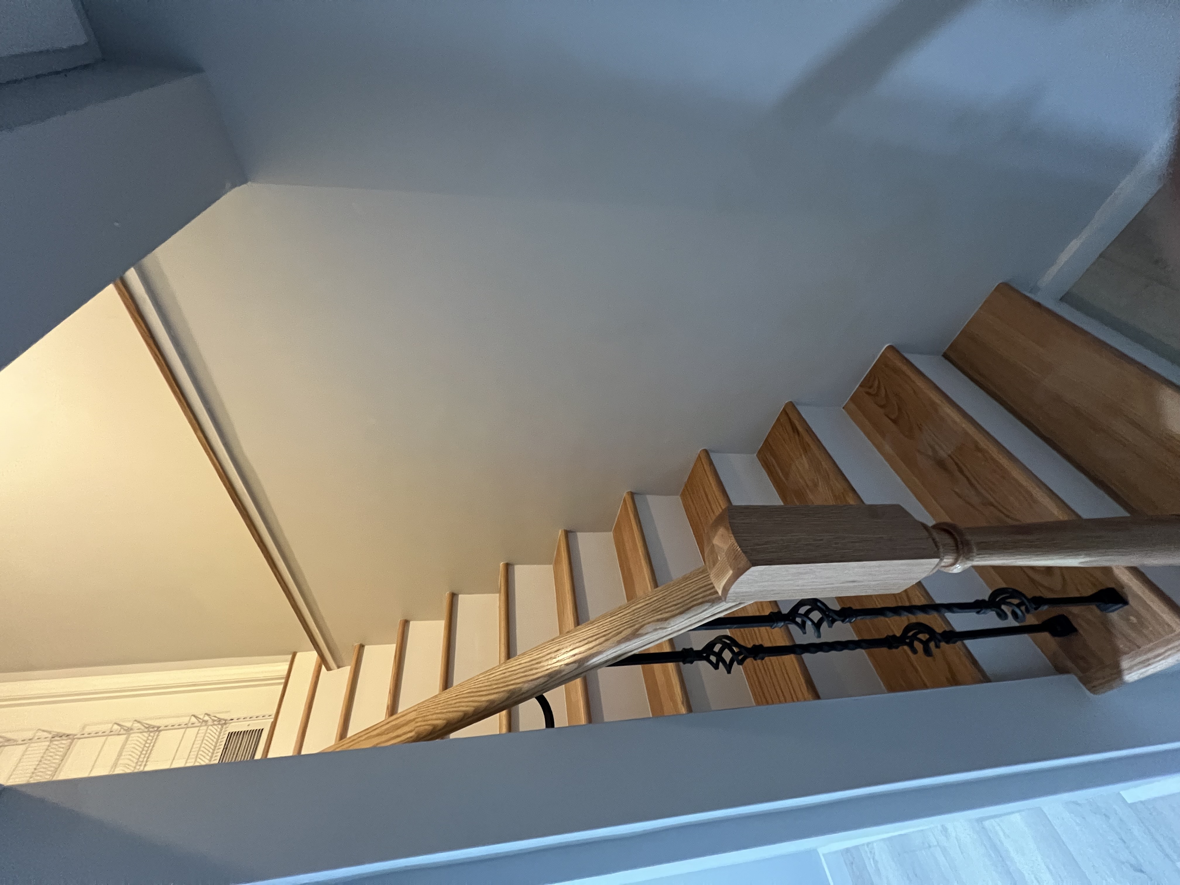 Staircase with wood rail, black balusters, and wood treads.