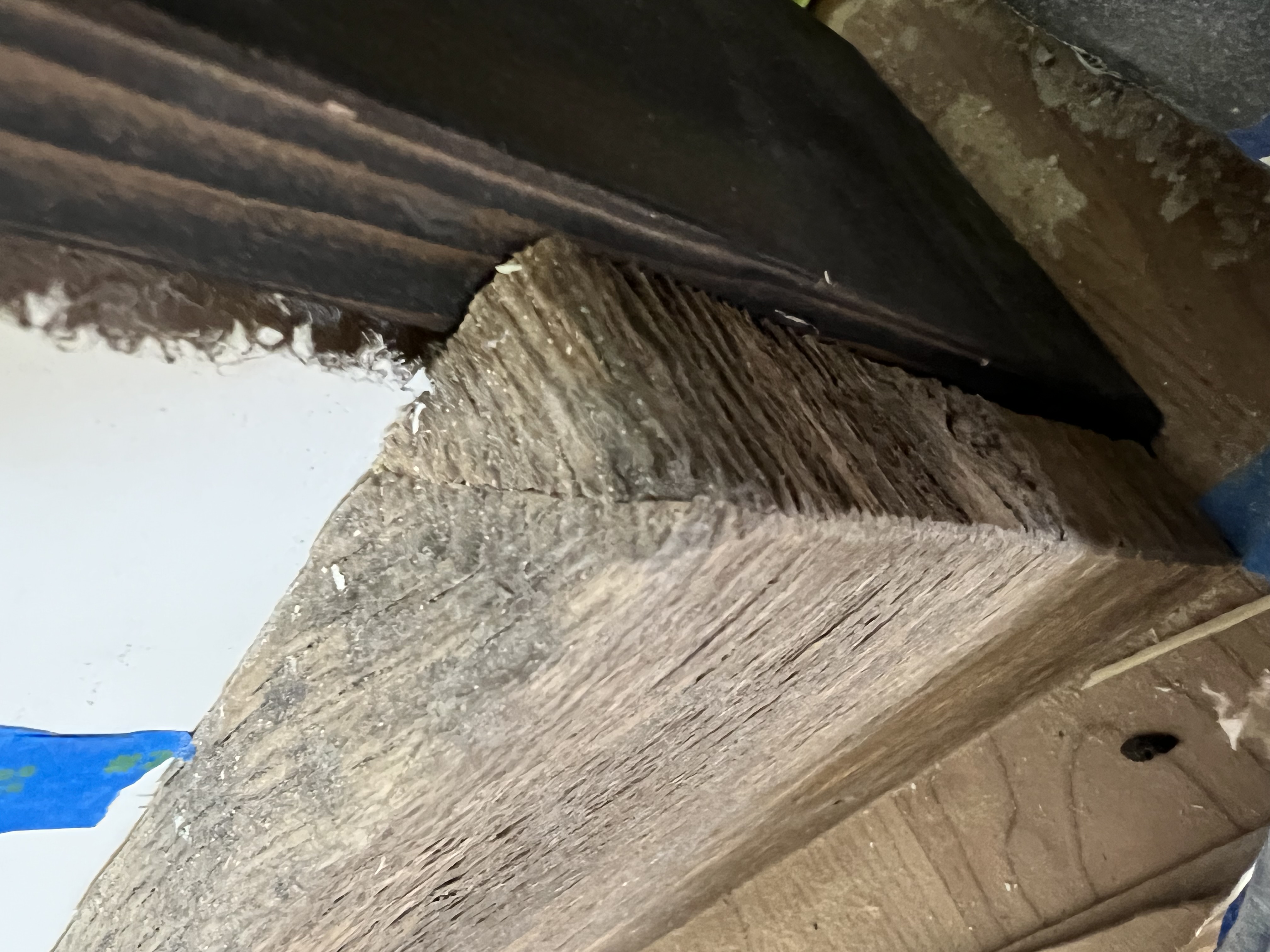 Close-up detail of mitered rustic wood trim beside a dark door frame.